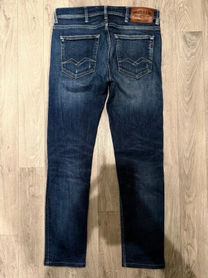 Replay Jondrill Jeans Mörkblå W30/L32 - Slim/Skinny Fit - Replay Jondrill mörkblå jeans med snygga slitningar och slim/skinny fit-passform som sitter smalt och bekvämt och funkar till allt, storlek W30/L32, midja 40 cm, ytterbenslängd 97 cm, benöppning 15,5 cm, modellen är 185cm & väger 65kg, i fint skick.