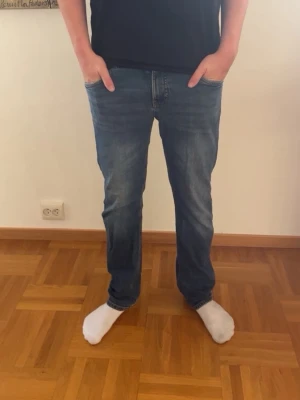 Blå raka jeans herr - Säljer ett par riktigt snygga och fräscha marinblå jeans från Kappahl – perfekt timing nu inför skolstarten! De har en klassisk, rak passform, normal midja med praktisk justering och fem fickor. Tillverkade i skön denim med lätt stretch för riktigt bra komfort hela dagen. Snygga, subtila slitningar ger en perfekt avslappnad look. 