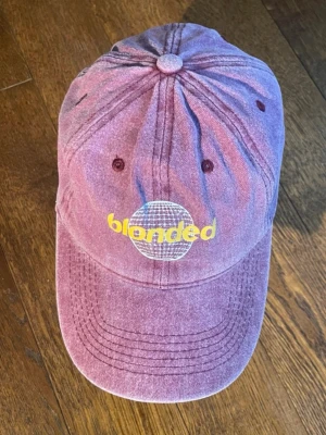 Frank Ocean Blonded Lila keps  - Säljer en lila Blonded keps. Kepsen har böjd skärm, justerbar rem bak och är tillverkad i bomullstyg med tvättad look. Perfekt för dig som gillar streetwear och vill sticka ut.