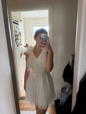 Ida Sjöstedt Darling Dress – Ivory, strl. 34 -  Otroligt fin klänning från Ida Sjöstedt, modell Darling Dress i  färgen Ivory. Klänningen har vackra stora blommor på axlarna, V-ringning och flera lager av skirt tyll som ger ett romantiskt och elegant fall. ✨  • Storlek 34 • Färg: Ivory • Nypris: 4 999 kr • Lapparna finns kvar • Mycket fint skick  Perfekt till student, bröllop, förlovning, möhippa eller annan festlig tillställning. 🤍🌸 