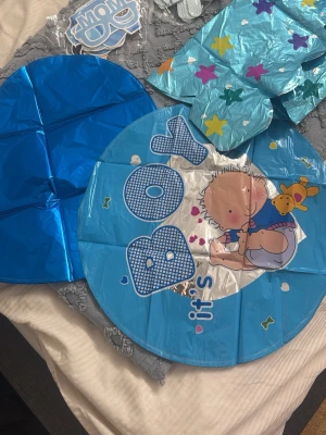 Blå folieballonger baby shower - Säljer ett set med blå folieballonger, bland annat en rund ballong med texten 'It's a boy' och en söt bebisillustration samt hjärtformade ballonger. Perfekt till baby shower eller gender reveal. Ballongerna har stjärnor och hjärtan som dekoration.