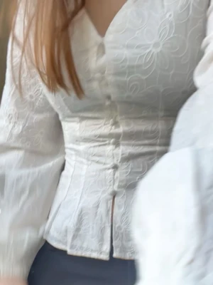 Vit blus med broderade blommor - Säljer en superfin vit blus med broderade blommor och knappar framtill. Blusen har v-ringning, långa ärmar och figurnära passform som ger en snygg siluett. Exakt kompia på adoore blusen nypris 599