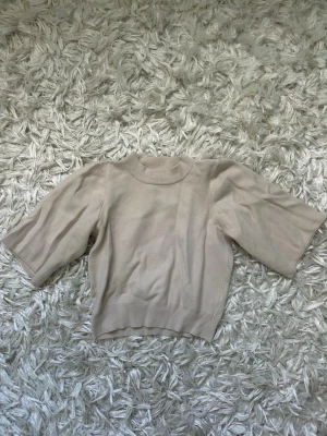 Beige tröja från Neo Noir - Säljer en snygg beige croppad tröja från Neo Noir med halvpolo och korta ärmar. 