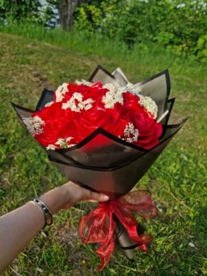 Bukett med röda rosor och vita blommor - Säljer en snygg bukett med konstgjorda röda rosor och små vita blommor, inslagen i svart och beige papper med en röd rosett. Perfekt som present eller dekoration till speciella tillfällen.