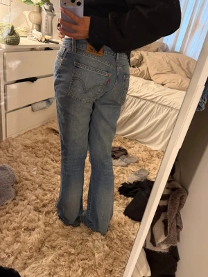 Blå raka Levi's jeans - Säljer ett par klassiska blå Levi's bootcut jeans. Jeansen har fem fickor, bälteshällor och den ikoniska läderlappen bak i midjan. Jag är 169 och passar bra i längden!