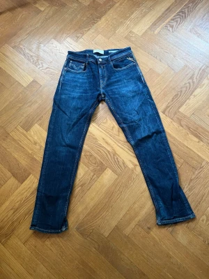Replay jeans  - Snygga mörkblå replay jeans med raka ben och klassiska fem fickor. Jeansen har kontrastsömmar och en liten detalj på höger ficka fram. Tillverkade i denim med en något tvättad look och normal midja. Comfort fit men sitter ganka smalt (sitter som slimfit) och bekvämt och funkar till allt. Använts fåtal gånger men ligger just nu i garderoben för det mesta och vill därför sälja den. 
