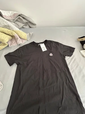  MȯncIer t-shirt - Snygg svart t-shirt från Moncler med klassisk rund hals och Moncler-logga på bröstet. Tillverkad i mjuk bomull som känns skön mot huden. Perfekt basplagg med stilren design och korta ärmar. Nytt med prislapp behöver sälja på grund behöver pengarna storlek M