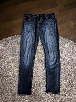 Mörkblå Levis 512 jeans - Snygga mörkblå slim fit jeans med klassisk femficksdesign och slitningar framtill. Jeansen har normal midja, dragkedjegylf och kontrastsömmar. Perfekta för en avslappnad och trendig look.