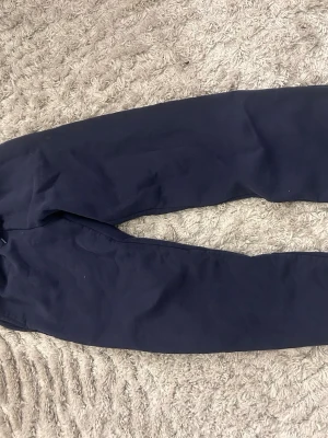 Mörkblå mjukisbyxor med resårmidja - Mörkblå mjukisbyxor med avslappnad passform och resår i midjan. Tillverkade i mjukt och bekvämt material, perfekta för chill dagar hemma eller när du vill vara extra comfy. Klassisk modell utan synliga loggor eller detaljer.