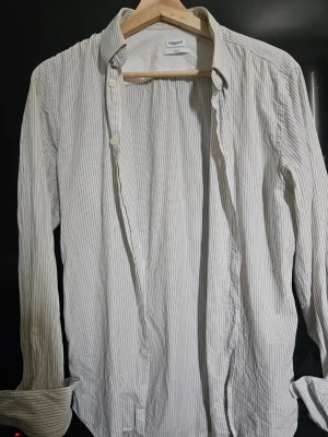 Vit randig skjorta från Filippa K - Snygg vit skjorta från Filippa K i storlek medium med tunna svarta ränder. Skjortan har klassisk krage, knäppning framtill och långa ärmar. Perfekt för en clean och stilren look. Passar perfekt som overshirt. Köpt för 1099 sek 