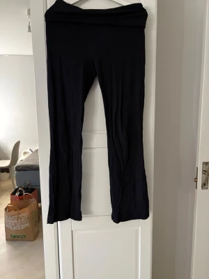 Mörkblåa utsvängda leggings - Säljer ett par mörkblåa leggings med utsvängda ben och hög midja. De är mjuka och stretchiga, perfekta för dig som gillar bekväma men ändå stilrena byxor. Materialet känns som bomull eller viskosblandning. Passar till sneakers eller boots.