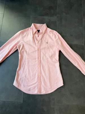 Ralph Lauren rosa skjorta  - Säljer min rosa ralph Lauren skjorta, då den är för liten för mig. Den är knappt använd och är i otroligt bra skick. Den är i storlek S. Hör av er vid frågar!