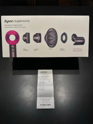  Supersonic hårfön med tillbehör -  Supersonic hårfön i silver och rosa med flera tillbehör: stylingmunstycke, smoothing nozzle, diffuser, gentle air attachment och flyaway attachment. Perfekt för olika hårtyper och stylingbehov. Modern design och hög prestanda. SKrive Innan köp tack. Det blot billigare om du betalar via cash 