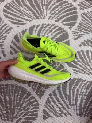 Neongula Adidas sneakers med svarta ränder - Snygga sneakers från Adidas i en riktigt iögonfallande neongul färg med svarta klassiska ränder på sidorna. Skorna har vit och grå sula, mesh-ovandel för bra andningsförmåga och snörning framtill. Perfekta för dig som gillar sportig stil och vill sticka ut.