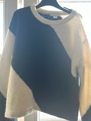 Stickad tröja med svart och vit blockdesign - Säljer en stickad tröja med cool blockmönster i svart och vitt. Tröjan har rund halsringning och långa ärmar. Från ginatricot i storlek 146/152
