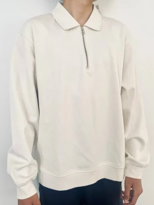Vit halvzip tröja med krage - Säljer en stilren vit långärmad tröja från Zara med halvzip och klassisk krage. Tröjan har en relaxed fit och är tillverkad i mjukt material, perfekt för en clean och enkel look.