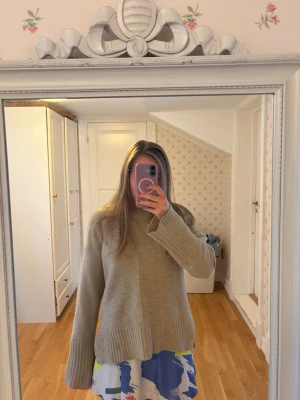 Beige oversized stickad tröja - Säljer en beige oversized stickad tröja med breda ribbade muddar vid ärmslut och nederkant. Tröjan har en avslappnad passform och är perfekt för lager på lager. Passar dig som gillar en enkel men trendig stil.