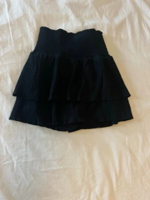 Svart volangskort skort - Supersnygg svart skort med hög midja och dubbla volanger. Skön att ha på sommaren.