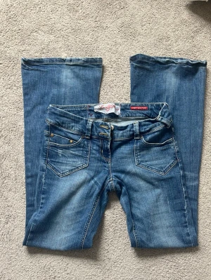 Blå bootcut jeans - Säljer ett par snygga River Island bootcut/flare jeans i klassisk mellanblå tvätt. Låg midja och figurnära passform över höfter och lår som går ut i en fin bootcut nedtill. Innerbenslängden är 81 cm och midjemåttet tvärsöver är 36 cm (se bild) Jeansen är i bra använt skick. Mindre tecken på användning finns, bland annat lite slitage längst ner vid bensluten, men inget som påverkar användningen.❣️