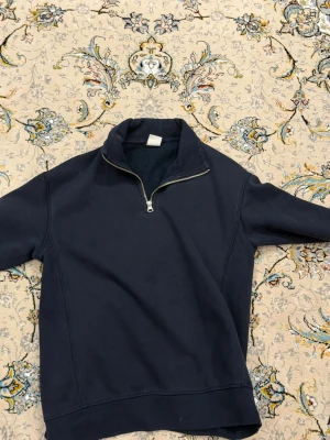 Mörkblå Zara quarter-zip sweatshirt - Mörkblå sweatshirt med halv dragkedja och hög krage. Tröjan har långa ärmar och en avslappnad passform, perfekt för en chill och stilren look. Materialet ser ut att vara mjukt och bekvämt, troligen bomull eller bomullsblandning.