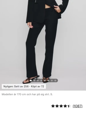 Svarta raka kostymbyxor - Stilrena svarta kostymbyxor med rak passform och pressveck. Byxorna har medelhög midja och långa ben som ger en snygg siluett. Perfekta att matcha med kavaj eller skjorta för en clean look. Materialet ser ut att vara en mjuk och följsam mix, troligen polyester eller viskos.