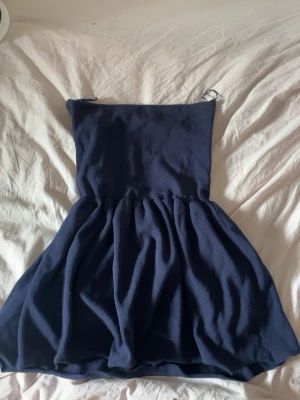 Marinblå axelbandslös topp - Söt marinblå topp med axelbandslös design och utställd kjol. Perfekt för varma dagar och enkel att styla med accessoarer. Tillverkad i mjukt tyg som ger en bekväm känsla.