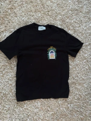 Casablanca tshirt  - Snygg svart t-shirt med färgglatt tryck från Casablanca på bröstet och stort motiv på ryggen. T-shirten har rund hals och korta ärmar. Perfekt för dig som vill ha en unik och trendig look.