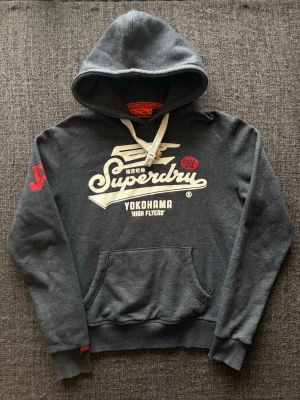 Superdry hoodie ~ sällsynt  - Superdry hoodie marinblå | st L men passar som M | Snygg hoodie i marinblå färg i fint skick. Sällsynt och eftertraktad modell som produceras ej längre och går knappt att få tag på. Vintage 2000’s modell. Perfekt nu till våren/sommaren 🏄 Kan även gå ner lite i pris vid snabb affär!