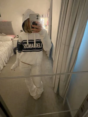 Vit Leksands IF hoodie  - Säljer en vit leksands if hoodie med huva och dragsnören. På bröstet finns en bred blå rand med vit text där det står 'LEKSANDS IF'. Perfekt för en chill och sportig look.