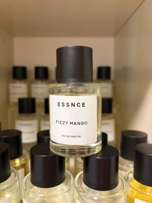 ESSNCE Fizzy Mango Eau de Parfum - Fräsch parfym från ESSNCE med doft av Fizzy Mango. Flaskan är cylindrisk i genomskinligt glas med svart rund kork och enkel vit etikett. Perfekt för dig som gillar fruktiga och upplyftande dofter.