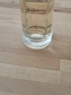 Baldessarini Eau de Cologne 75 ml - Baldessarini Eau de Cologne från Hugo Boss i en stilren, rund glasflaska med transparent vätska. Flaskan har elegant svart text och metallfärgad kork. Klassisk och tidlös doft för dig som gillar exklusiva parfymer. Och nu är den väl 60 ml kvar 