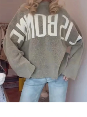 Söker Beige oversized stickad tröja - Söker denna  oversized stickad tröja med stora vita bokstäver över bröstet. Tröjan har breda ärmar och ribbstickade muddar vid ärmslut och nederkant. Perfekt för en avslappnad och trendig look.