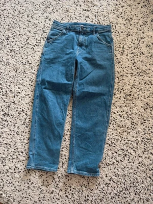 Blå raka jeans från Uniqlo - Säljer ett par klassiska blå jeans från Uniqlo med rak passform och hög midja. Jeansen har fem fickor, bälteshällor och stängs med knapp och dragkedja. Perfekta till vardags och lätta att matcha med olika stilar.