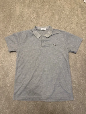 Lacoste Piké  - Säljer en grå Lacoste piké-tröja i nyskick till riktigt bra pris. Säljer dom enbart för att rensa lite hemma och att jag behöver bli av med de så snabbt som möjligt. Kontakta mig vid frågor eller funderingar.
