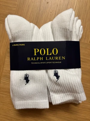 Polo Ralph Lauren strumpor - 6-pack vita ribbade strumpor från Polo Ralph Lauren med den klassiska mörkblå loggan broderad vid ankeln. Strumporna är i sportig modell och passar perfekt till sneakers eller träning. Snygg och enkel design som funkar till det mesta.