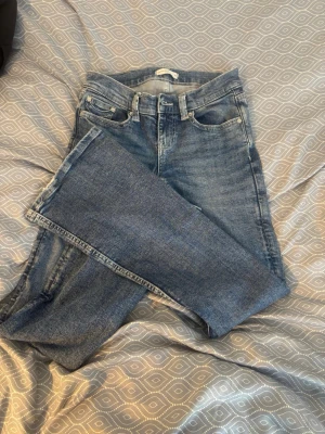 Blå bootcut jeans i klassisk modell - Säljer ett par blå bootcut jeans lowwaisted. Lite slitet vid nedre benet. 
