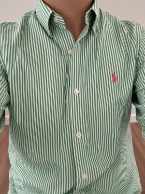 Grön och vitrandig skjorta från Polo Ralph Lauren (Slim Fit) - Säljer en grön- och vitrandig skjorta från Polo Ralph Lauren med klassisk krage och långa ärmar. Skjortan har knappar framtill och den ikoniska rosa logotypen broderad på bröstet. Perfekt för dig som gillar stilrena och tidlösa plagg. Storlek M. Snabb Leverans!