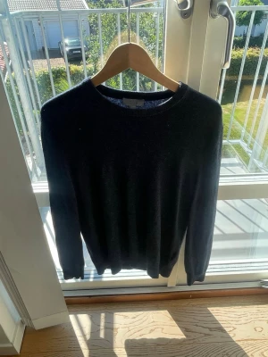 Mörkblå stickad tröja från COS - En stilren mörkblå stickad tröja från COS med rund halsringning och ribbade muddar. Perfekt för lager på lager och enkel att matcha med olika outfits. Tillverkad i mjukt material som känns skönt mot huden.