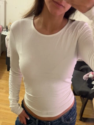 Vit långärmad tight topp - Säljer en enkel och stilren vit långärmad topp med rund hals. Materialet känns mjukt och stretchigt. Perfekt basplagg för garderoben. Se bion🫶🏻