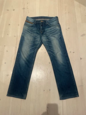 Edwin Jeans - Snygga blå jeans med raka ben och slitningar framtill. Jeansen har kontrastsömmar och detaljerade bakfickor med bruna inslag. Klassisk femficksmodell i denim, perfekt till vardagslooken. Materialet är bomullsdenim.