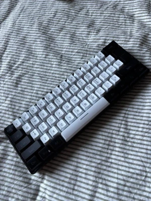 Svartvit kompakt tangentbord - Säljer ett kompakt mekaniskt tangentbord med svart och vita tangenter. Tangentbordet har en minimalistisk design och passar perfekt för dig som vill ha ett smidigt och portabelt alternativ till datorn. Tangenterna är i plast och layouten är svensk.