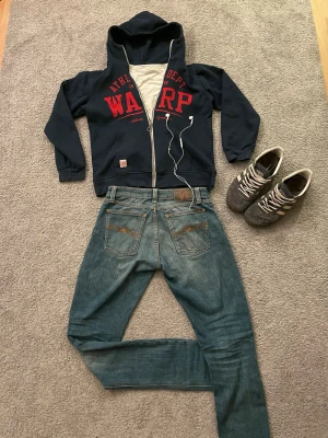Mörkblå hoodie M/C - Snygg mörkblå hoodie med dragkedja. Klassisk huva och två fickor på magen. Tillverkad i mjukt bomullsmaterial, perfekt för en avslappnad streetwear-look. Storlek =158-164cm =XS.   Säljer även Nudie Jeansen.