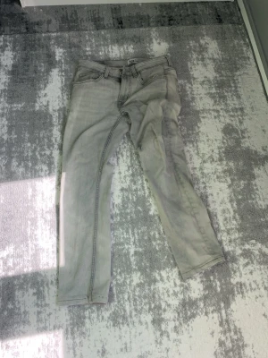 Ljusgrå raka jeans - Säljer ett par ljusgrå jeans med rak passform och klassisk femficksdesign. Jeansen har normal midja och är tillverkade i ett mjukt denimtyg. Perfekta för en avslappnad och stilren look.