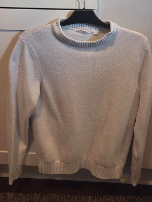 Ljusgrå stickad tröja från Dobber - Snygg ljusgrå stickad tröja från Dobber med rund halsringning och ribbade muddar vid ärmslut och nederkant. Perfekt för lager på lager och enkel att matcha med olika stilar. Materialet känns mjukt och bekvämt.