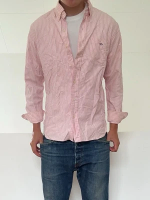 Rosa och vit randig skjorta - Rosa Randig Ralph Lauren skjorta i strl L men sitter mer som en M! Bra skick utan nåra defekter och hör gärna av er vid frågor elr funderingar!!