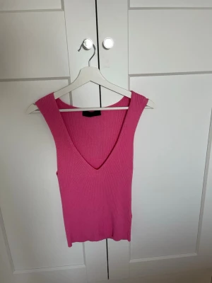 Ribbad rosa linnetopp från Zara - Säljer en ribbad rosa linnetopp från Zara med djup v-ringning och ärmlös design. Perfekt för dig som gillar en enkel men snygg look. Materialet är stretchigt och följsamt för en bekväm passform.