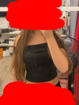 Svart axelbandslös tubtopp - Säljer en svart axelbandslös tubtopp med slät finish. Toppen är croppad och sitter tight mot kroppen, perfekt för en trendig och enkel look. Materialet känns mjukt och följsamt mot huden.