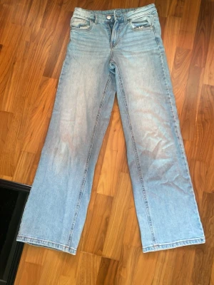 Ljusblåa raka jeans med hög midja - Säljer ett par ljusblå jeans med rak passform. Jeansen är tillverkade i denim med en snygg tvätt. Perfekta för en avslappnad och trendig look.