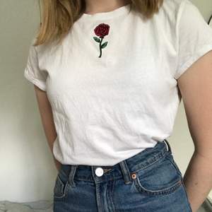 Vit t-shirt med en ros frampå