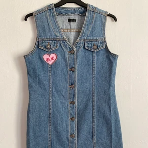 Jeansklänning med text - Jeansklänning i 60-talsmodell. Text på baksidan och patch fram. 